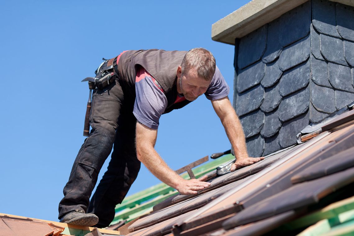 A roofer making repairs on a roof