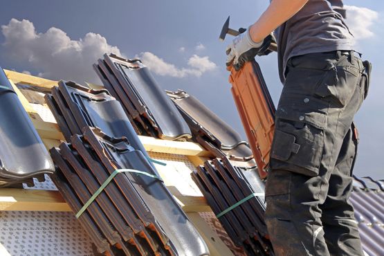 Roofer installing new roof tiles